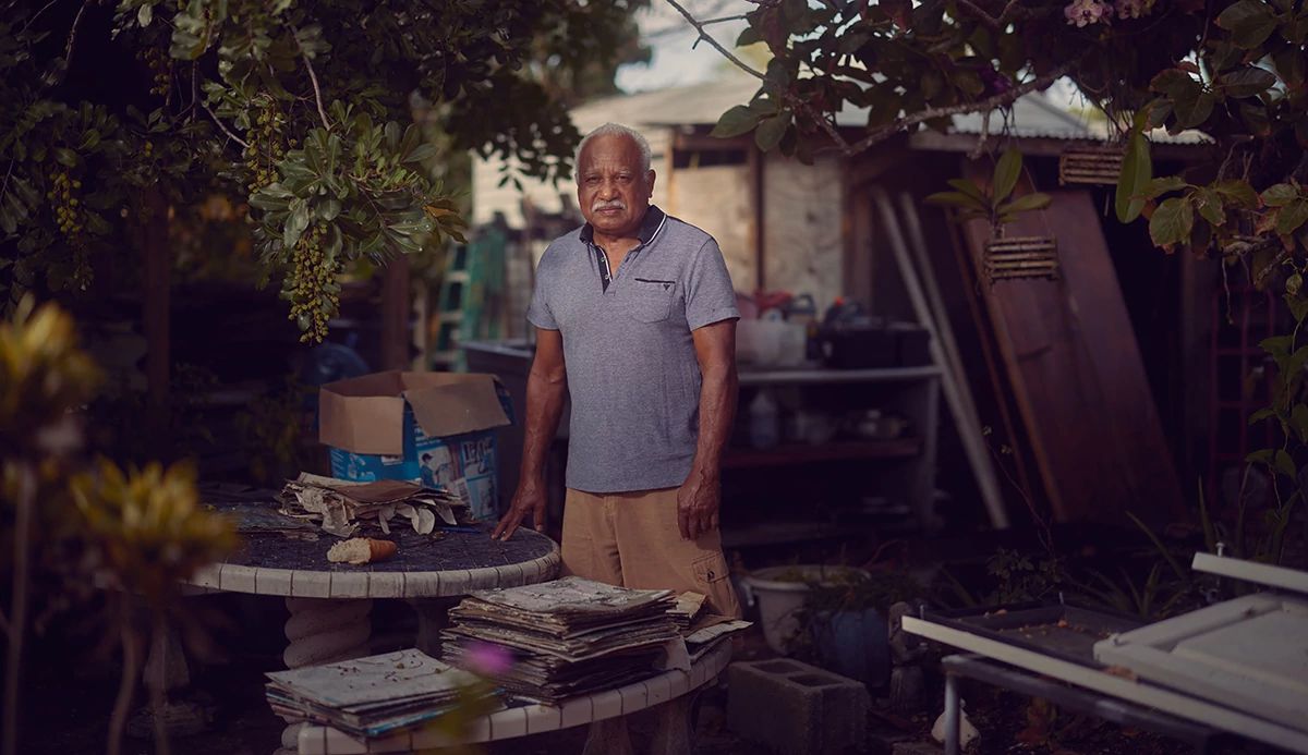 A man in a blue shirt stands behind a round table outdoors