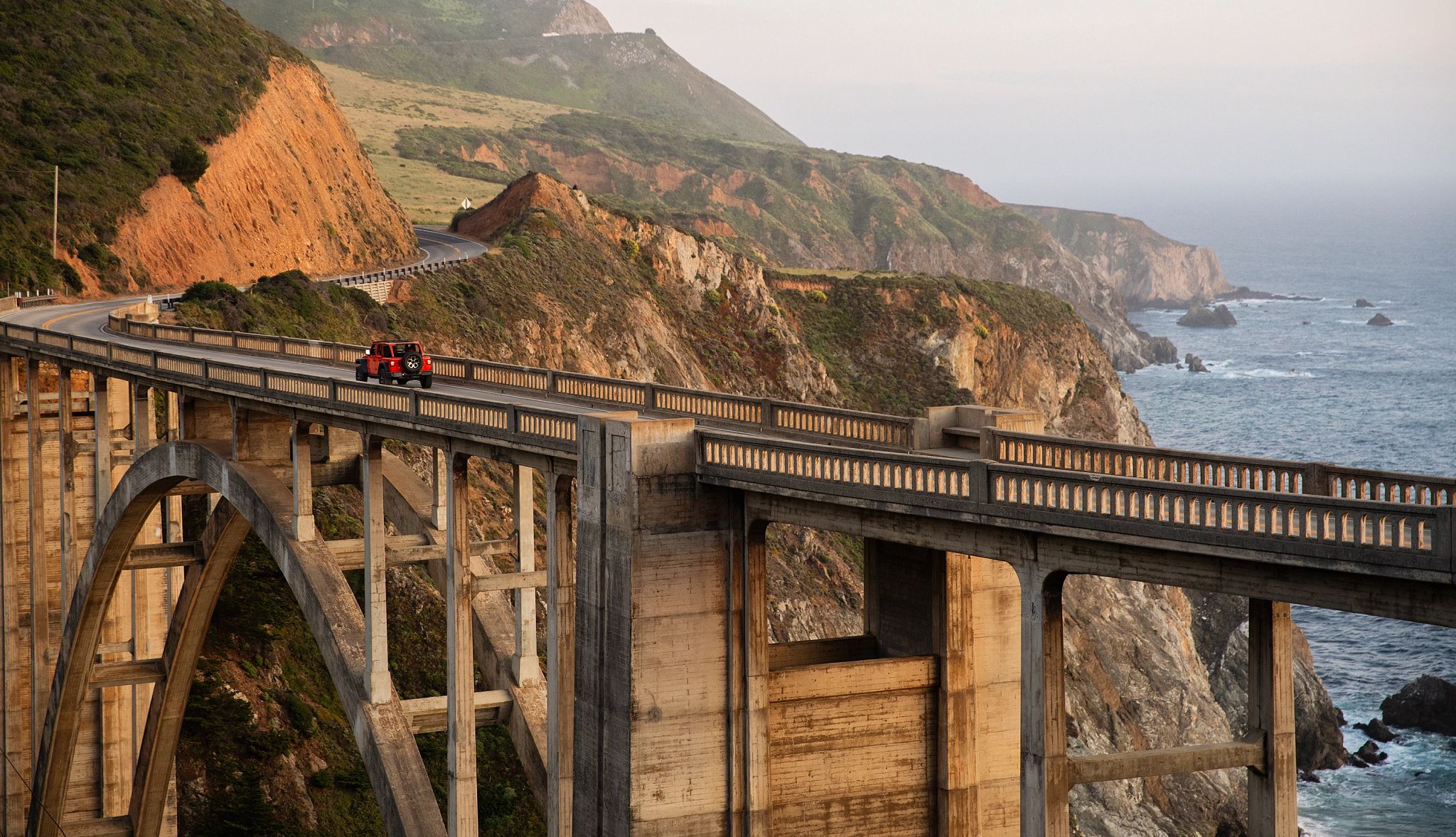cruise along Highway 1 a red jeep drives along the famous Bixby Creek Bridge in Monterey County