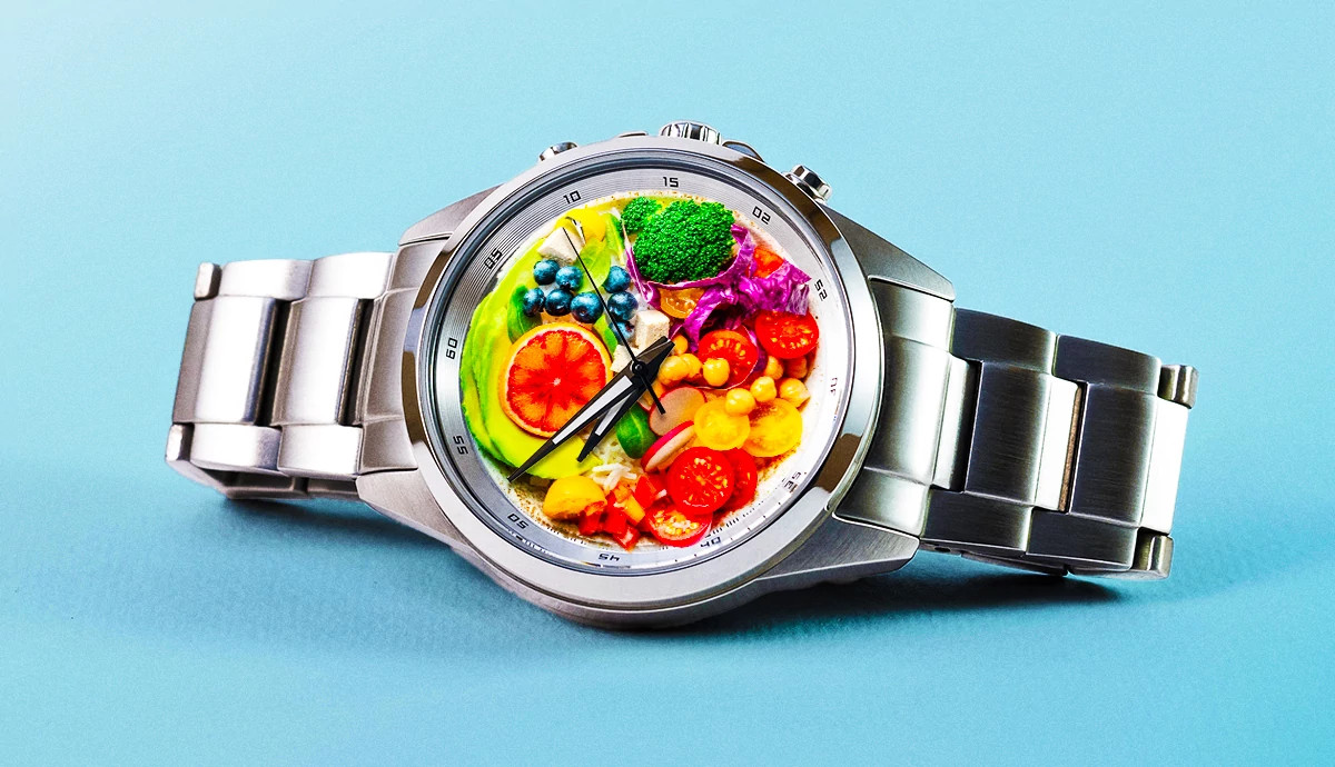 an analog watch with an assortment of fruits and vegetables on the watch face