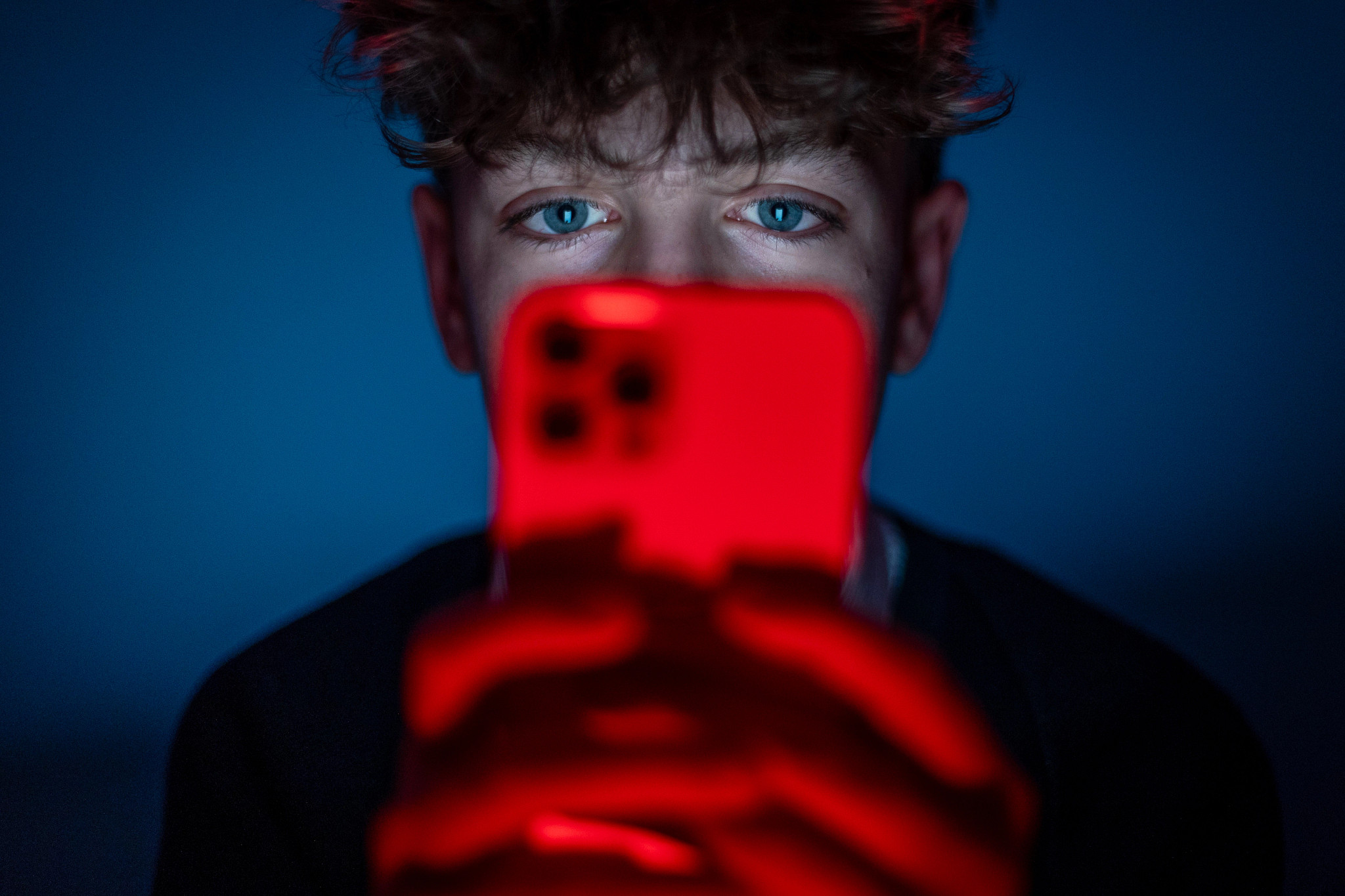 a photo shows a teenage boy looking at a smartphone screen