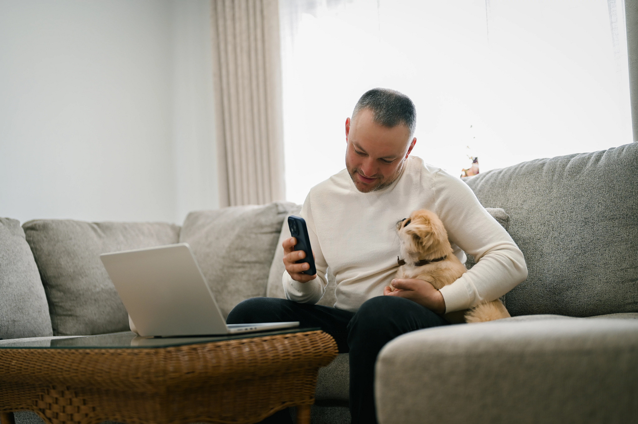 a person sitting on a couch with a dog while holding up a phone