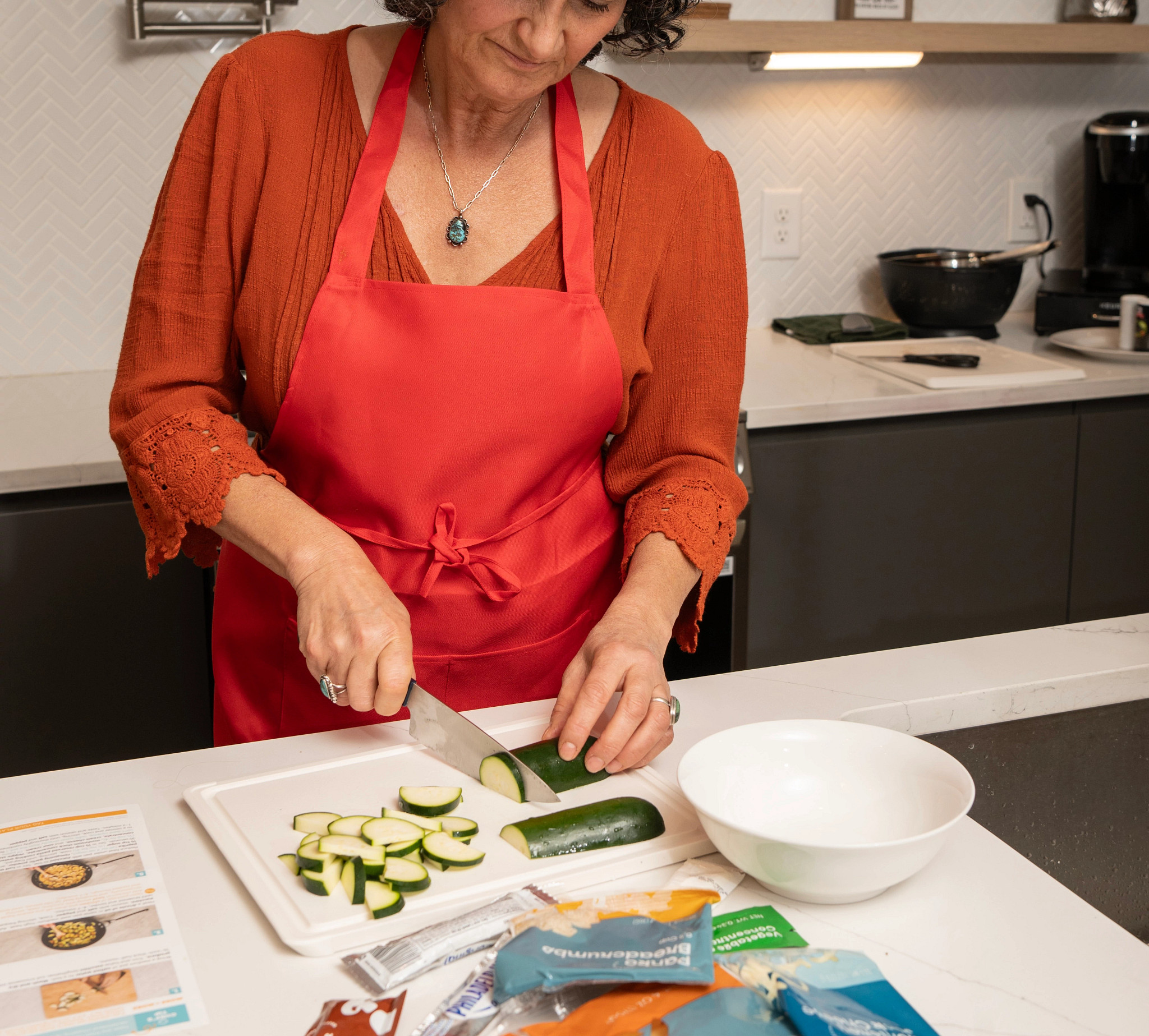 A woman chopping a zucchini from her Everyplate meal kit.