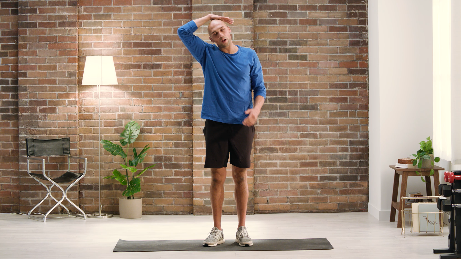 Adrian Davis standing on mat, reaching right arm around head and stretching head and neck to the right