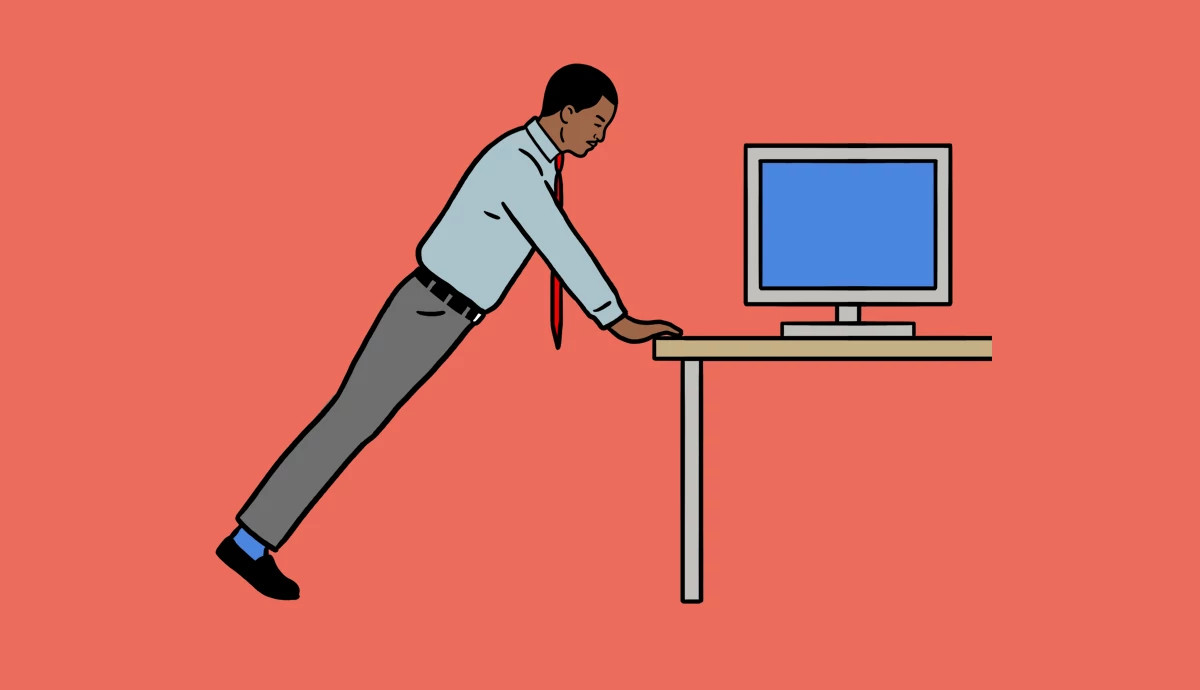 A man does a plank move with his hands on the edge of a desk.
