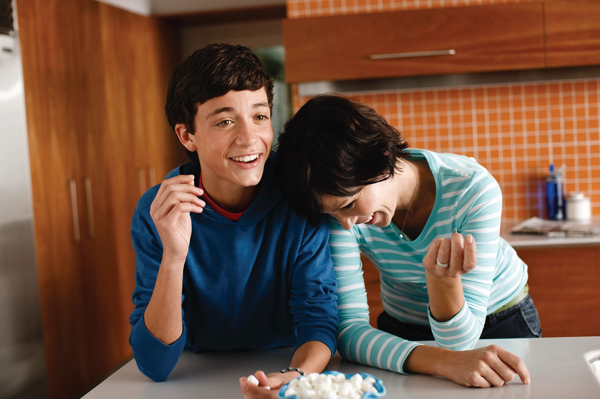 Mother and her teenage son laughing in their kitchen