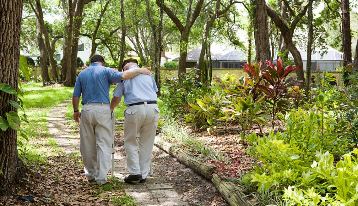 Alzheimer’s and other dementias affect millions of families A man with his arm around the shoulder of another man using a walker in a park