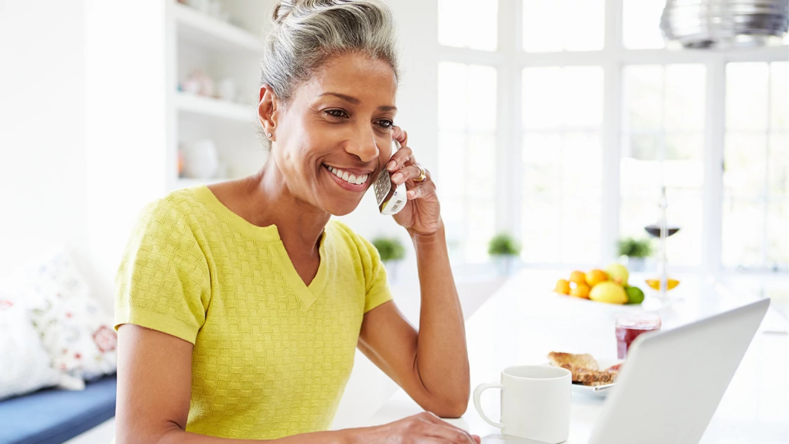 lady smiling on phone working on a laptop