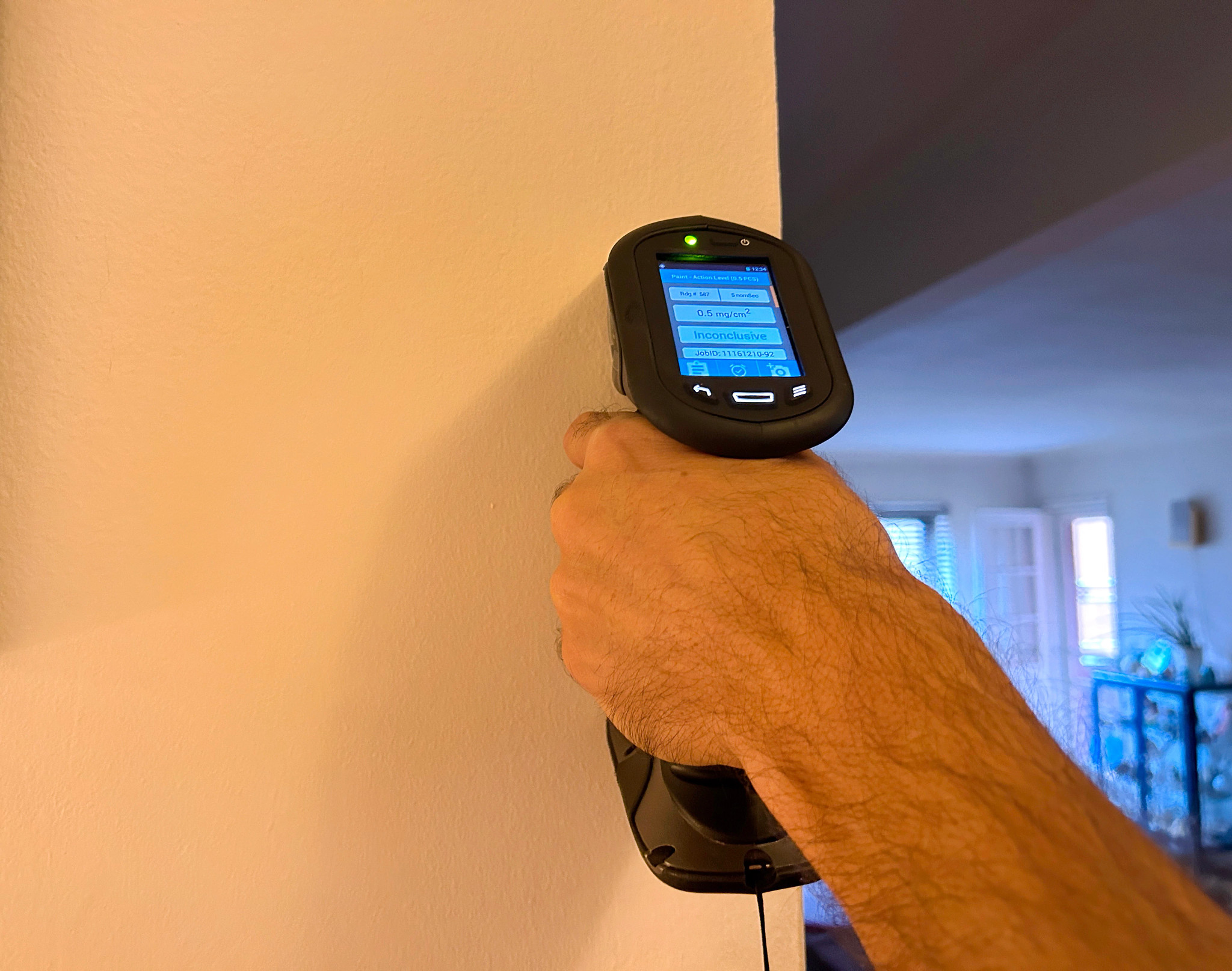 hand holding a lead paint detector to a wall