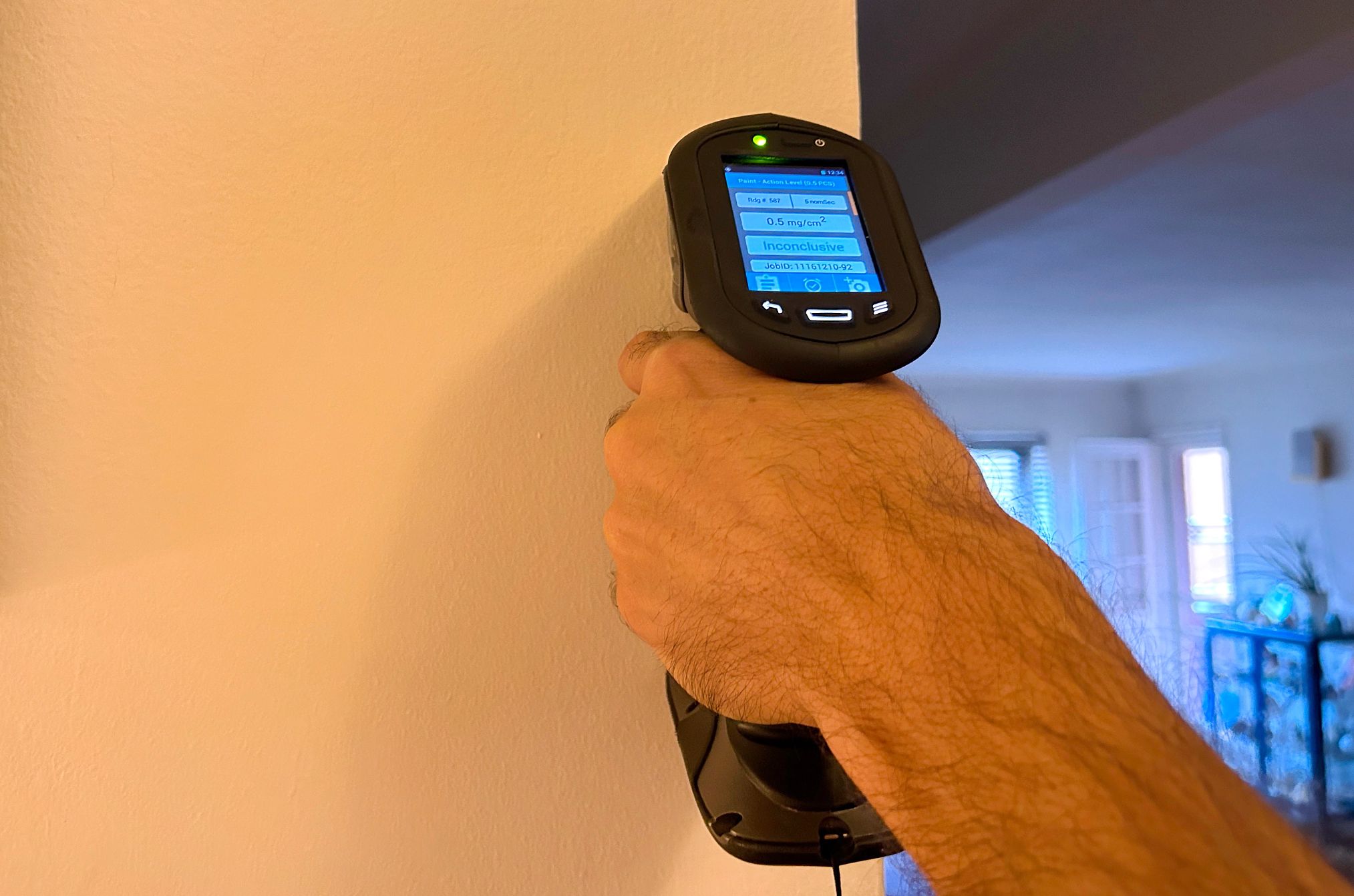 Use a professional inspector to find lead paint hand holding a lead paint detector to a wall