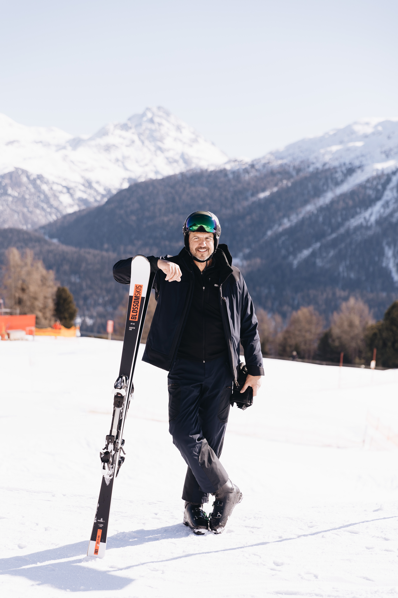 Chef Andrea Berton standing in the snow with a pair of skis