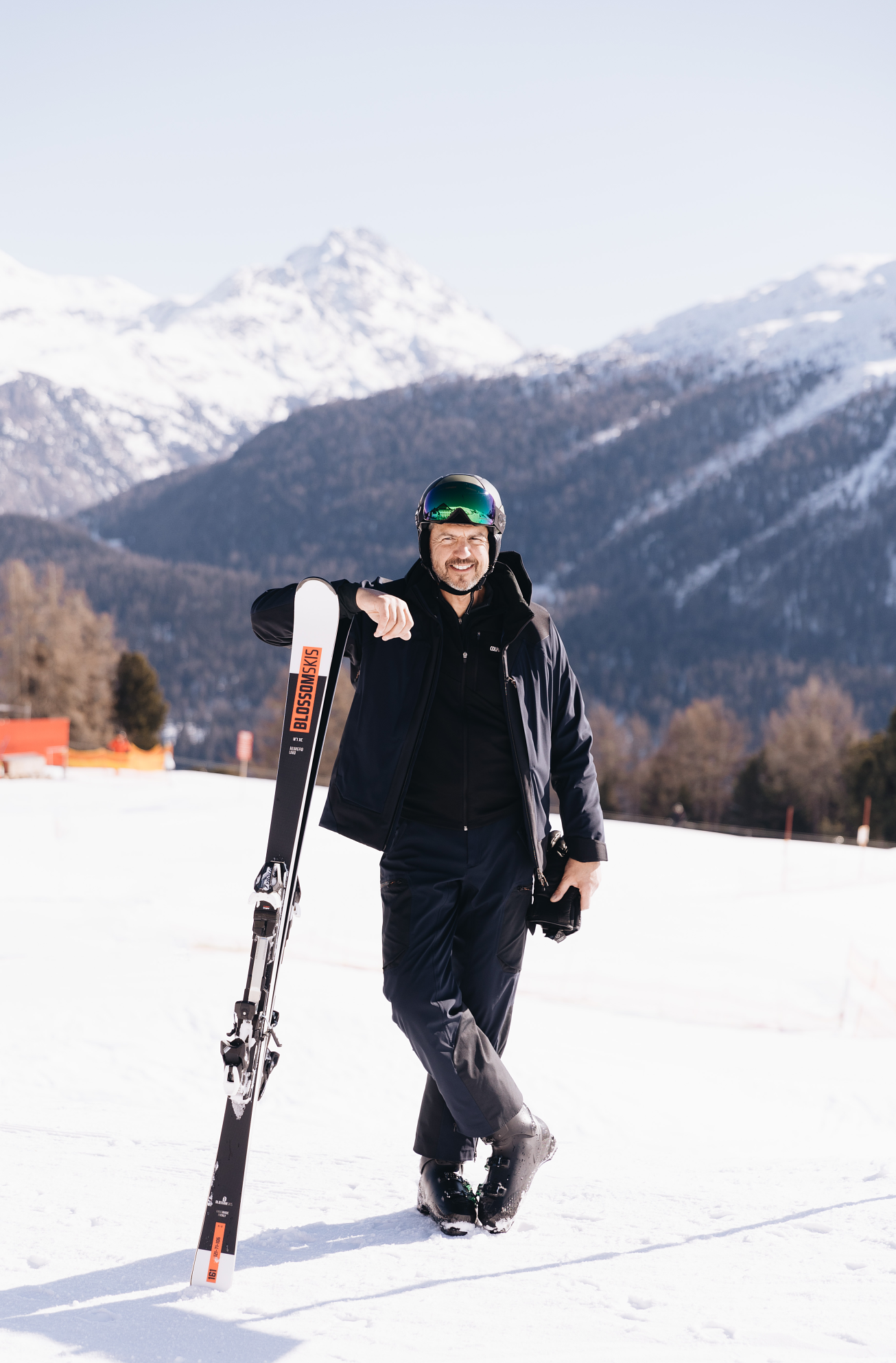 Chef Andrea Berton standing in the snow with a pair of skis