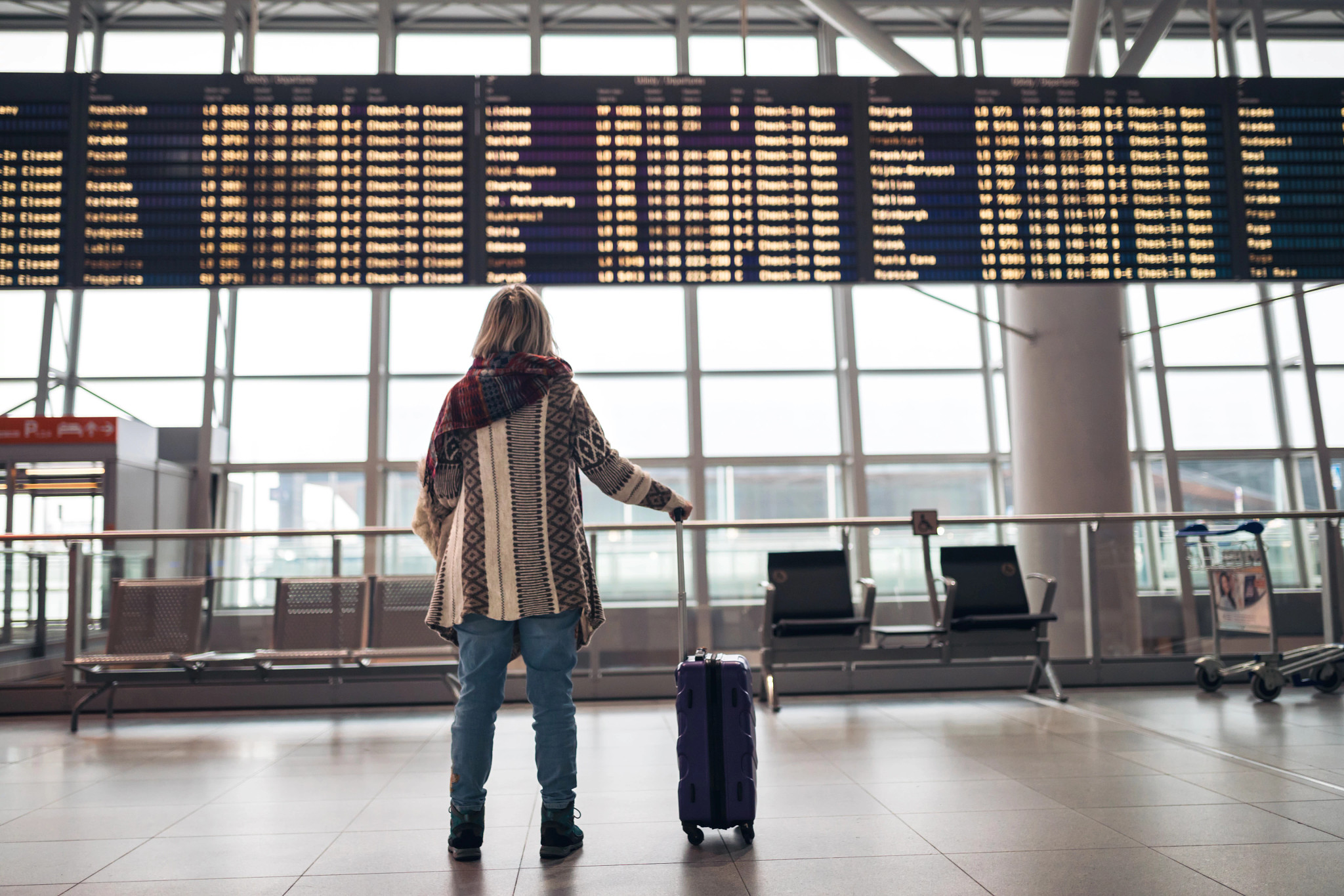 woman looking at arrival and departure board at an airport