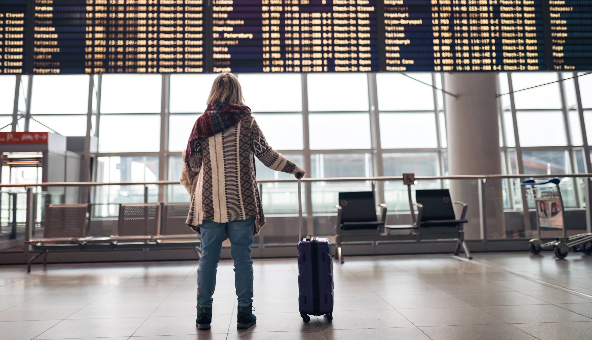 woman looking at arrival and departure board at an airport