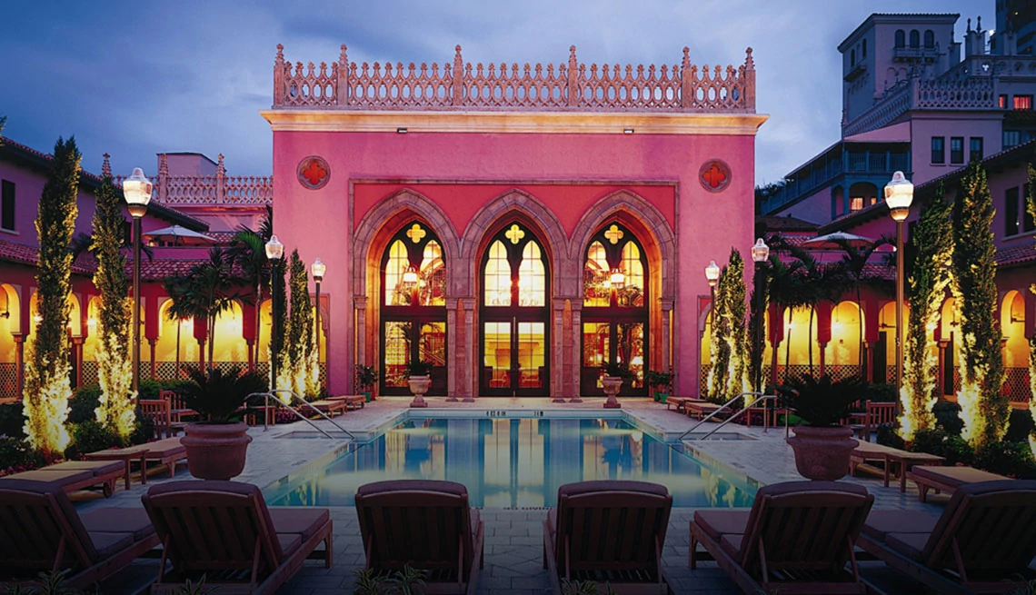 pink exterior to hotel with large windows and doors and pool 