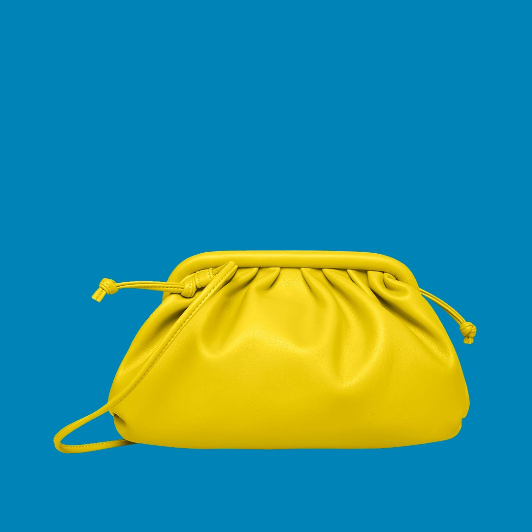Bright yellow leather clutch purse with gathered top and drawstring closure displayed against a blue background