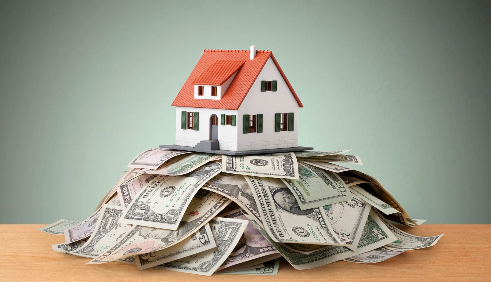 a miniature house on top of a stack of bills
