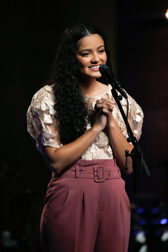 The Voice contestant Madison Curbelo standing in front of a microphone during the Season 25 Pretaped Playoffs