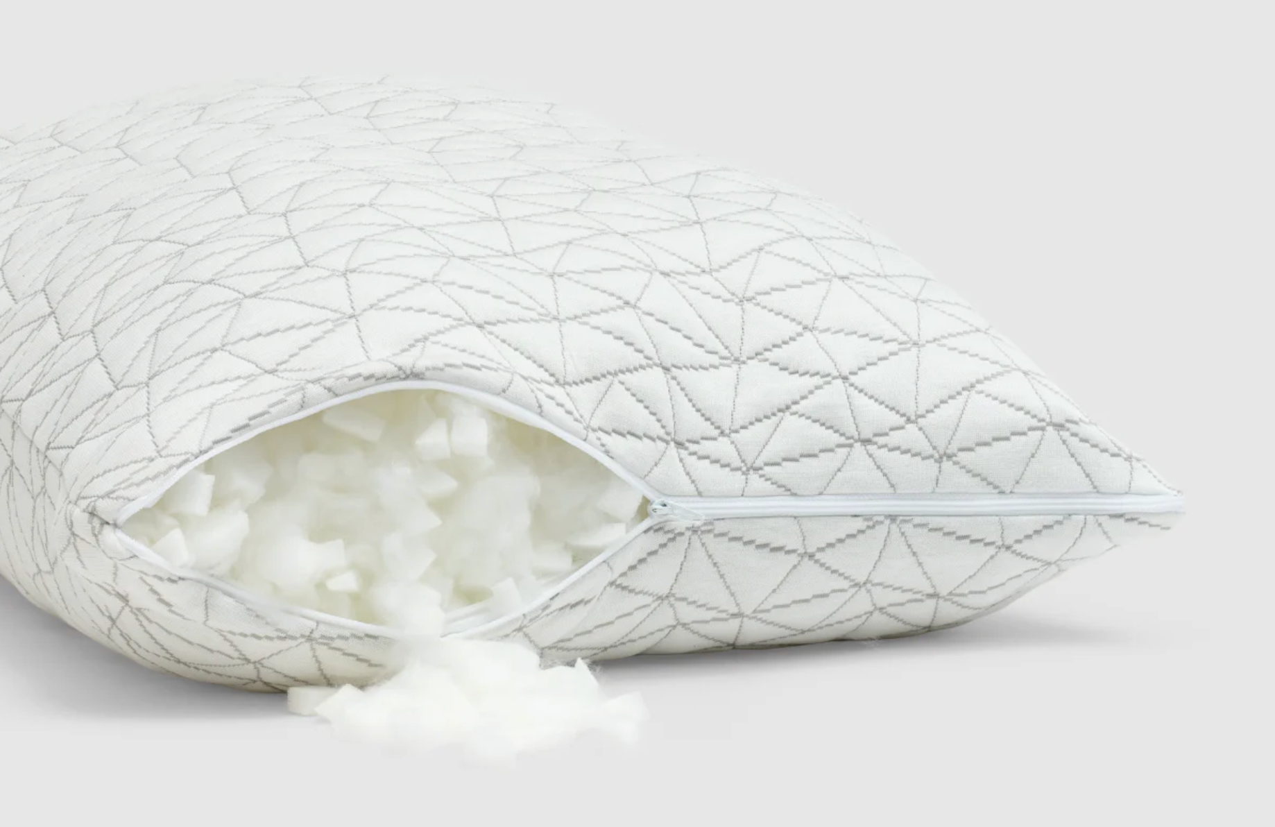The Coop Original Adjustable Pillow lying flat on a white background with the cover zipper partially open to show the filling inside