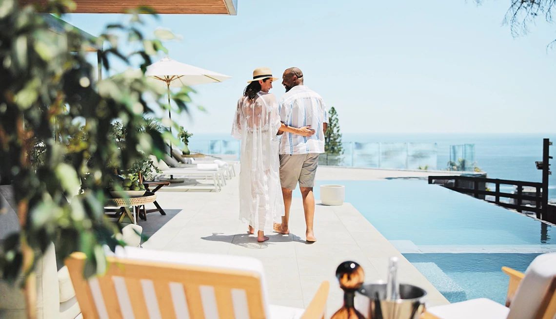 Couple standing next to an infinity pool with ocean view while on vacation at a luxury resort