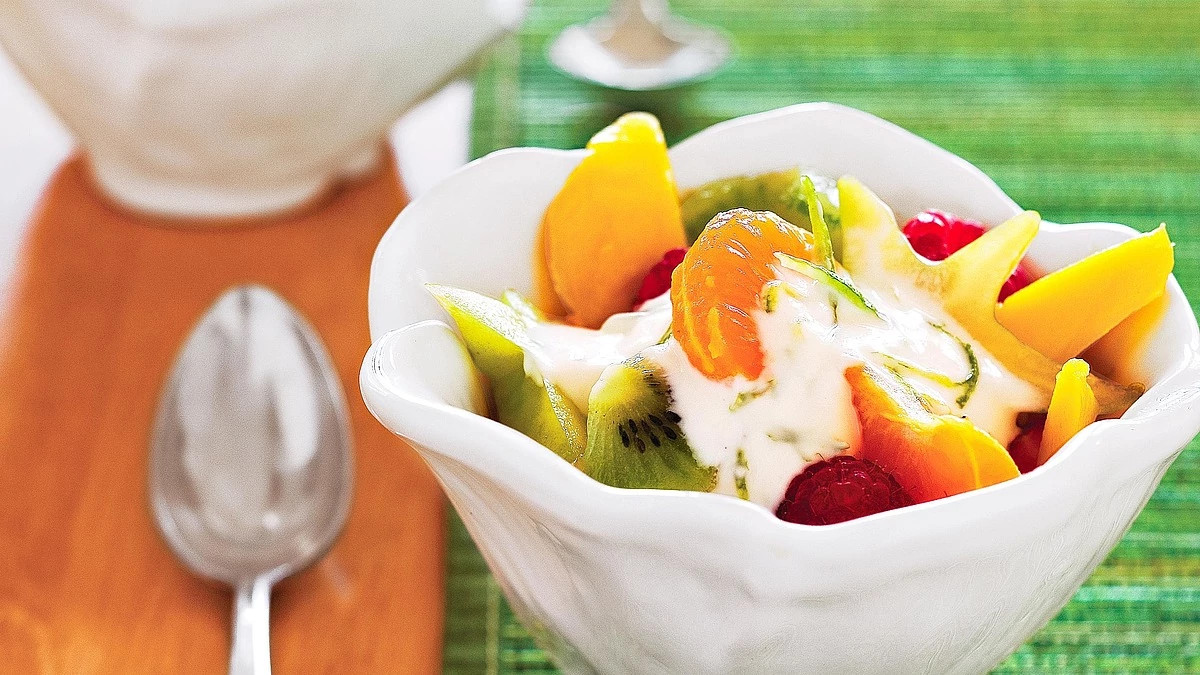A close-up view of fresh fruit salad with creamy lime topping in a bowl