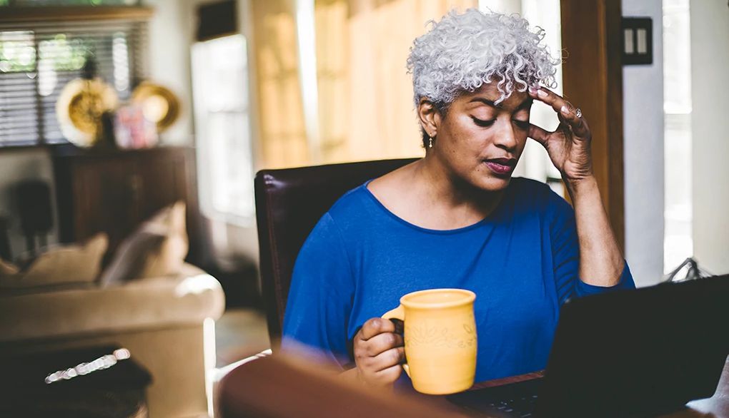 Finding ways to lower your stress may be beneficial for your well-being A woman appearing stressed while working on laptop on a table at home