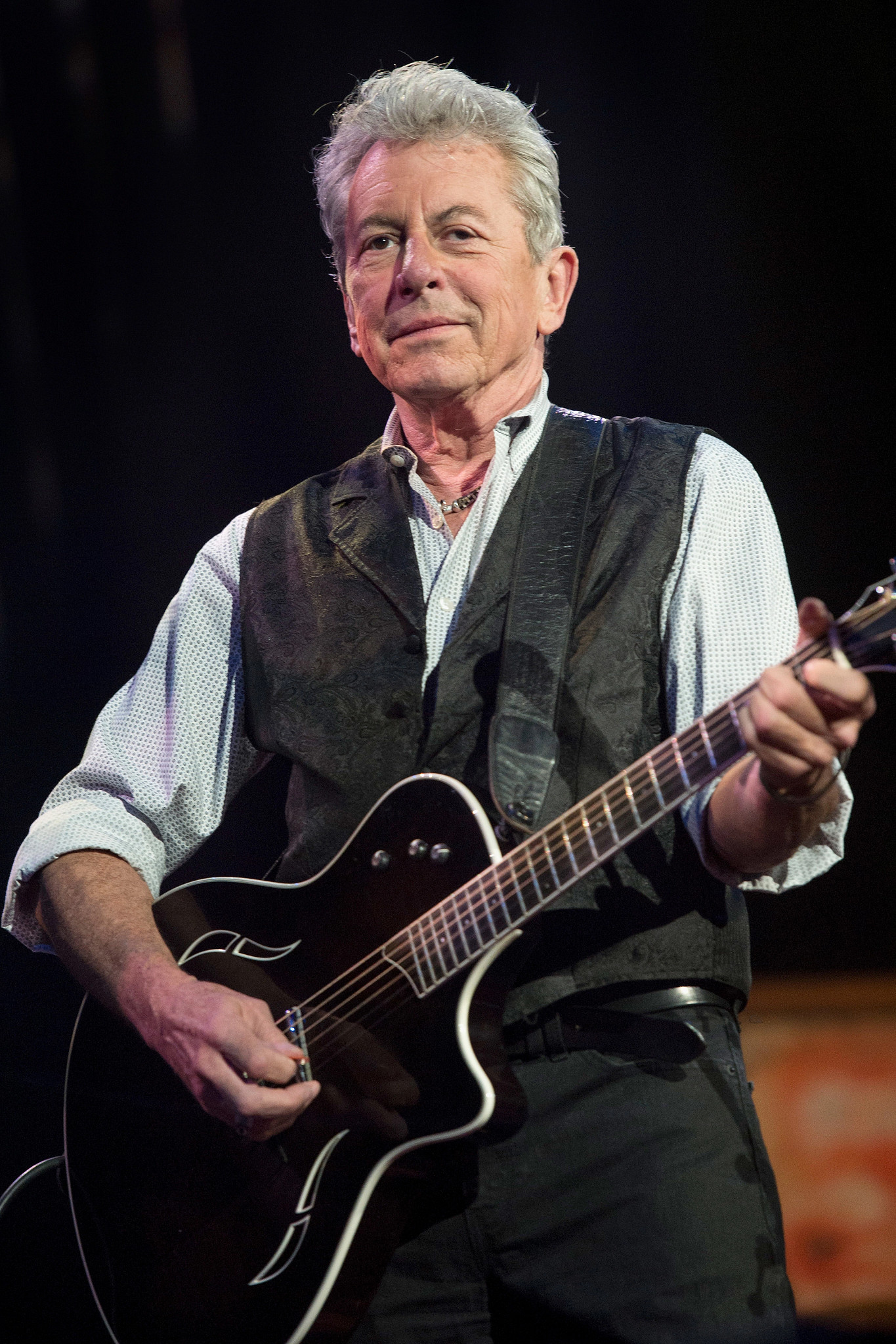 joe ely performs onstage with a guitar