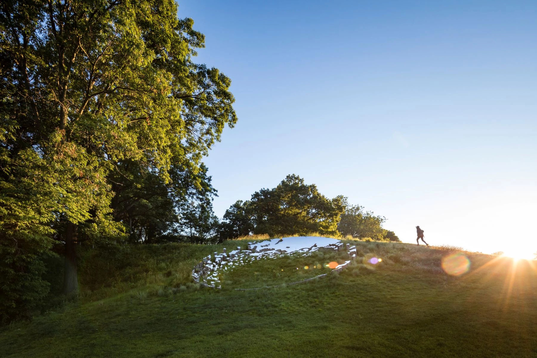 a person walking near a piece of art in a field