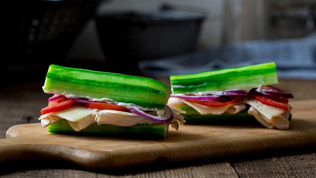 A close-up view of a cucumber turkey sub sandwich on a cutting board