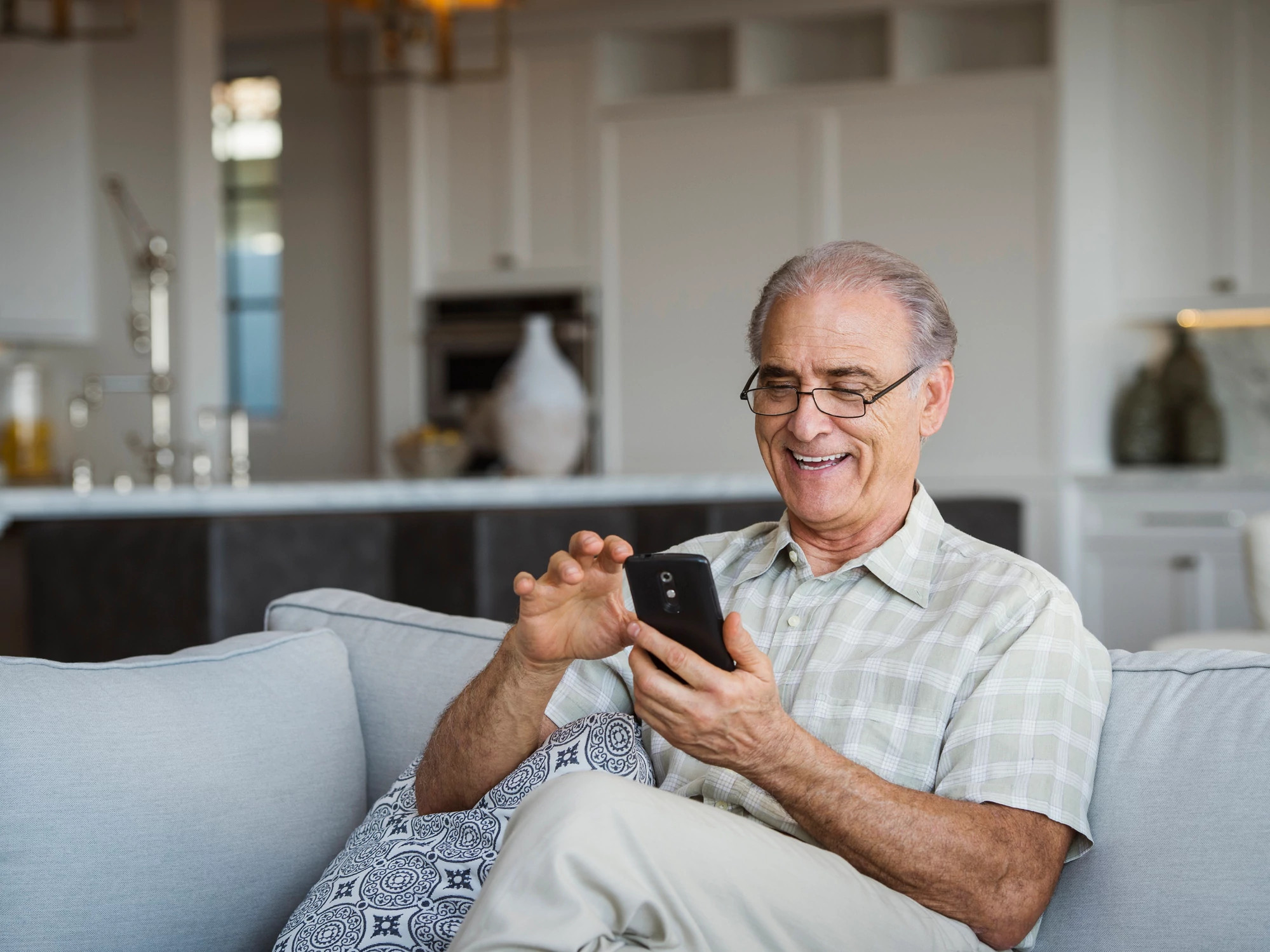 Man sitting on a sofa using cell phone.