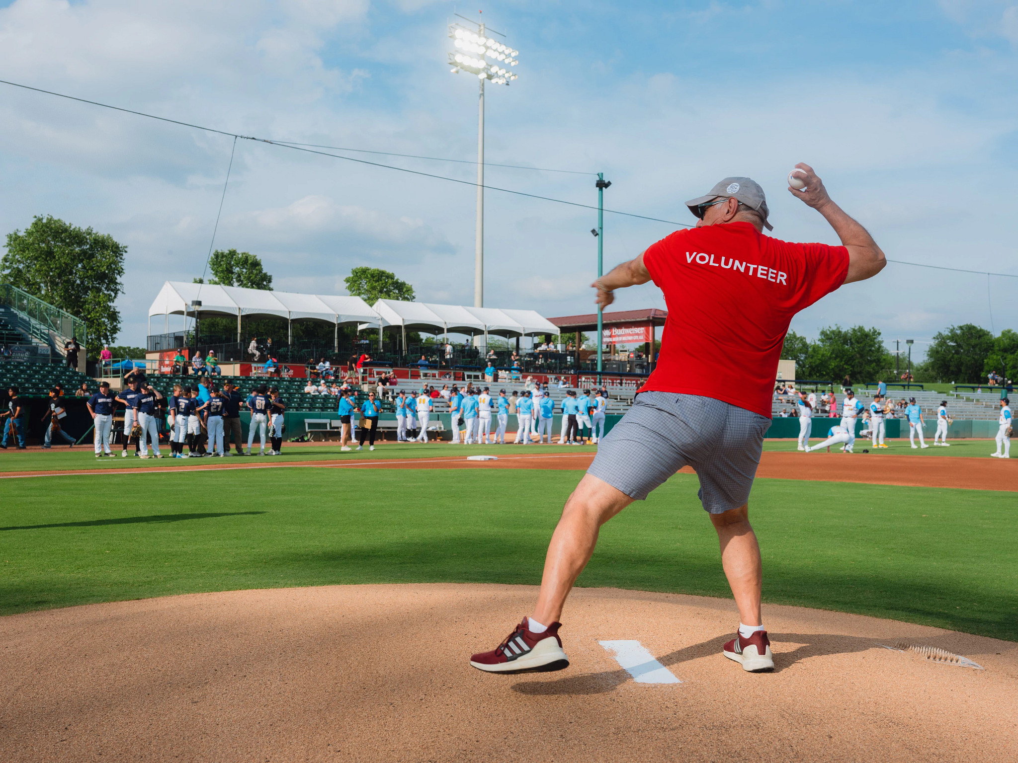 a man in a red AARP shirt throwing a baseball