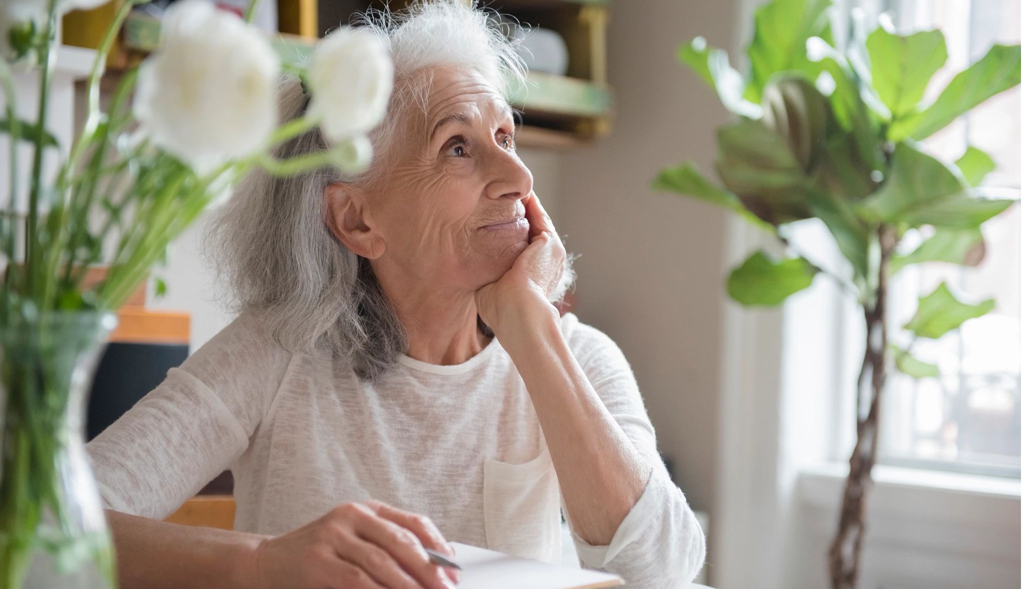 Woman journaling and looking out the window Woman journaling and looking out the window