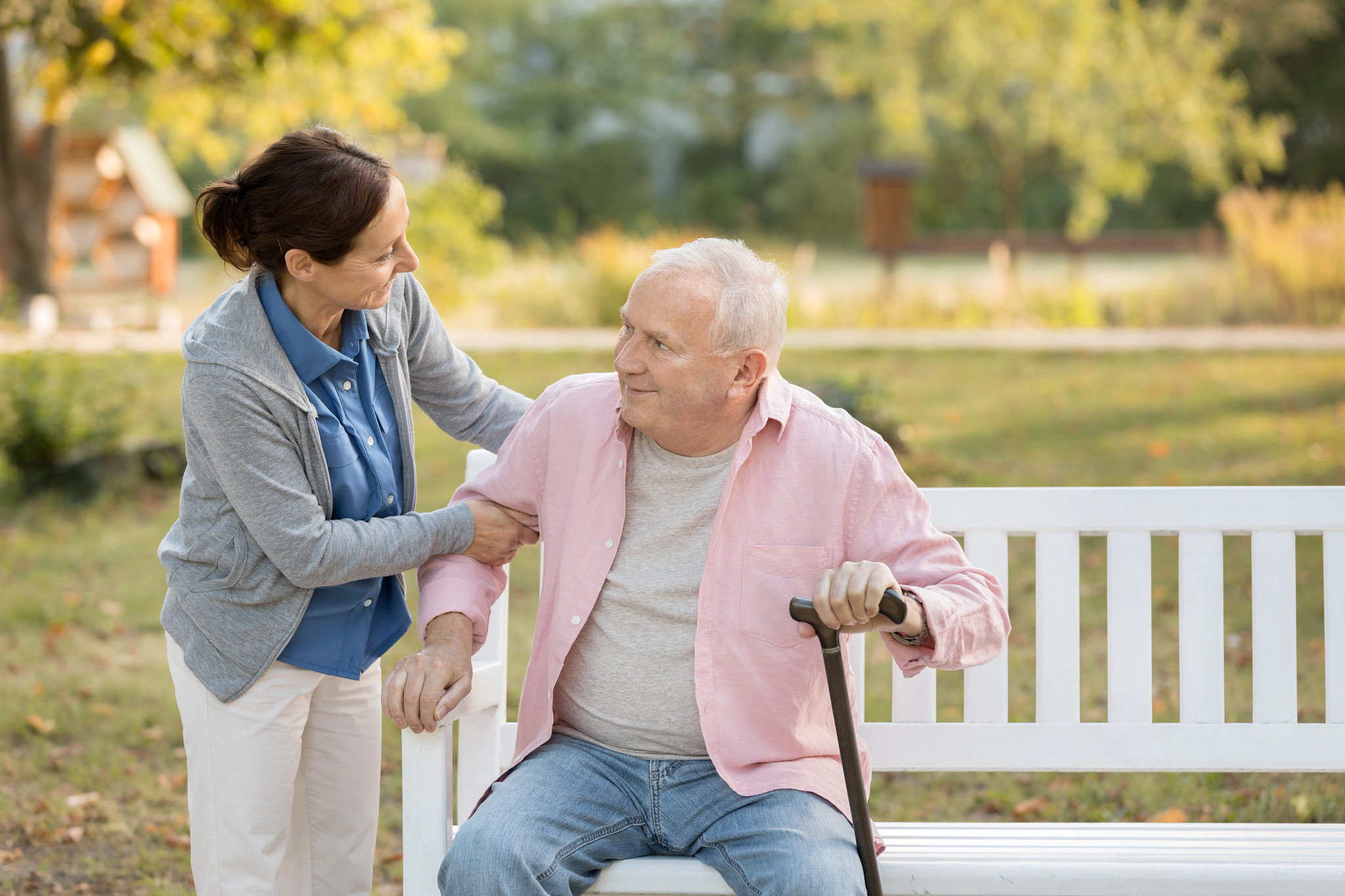 Caregiver with older gentleman at a park bench.