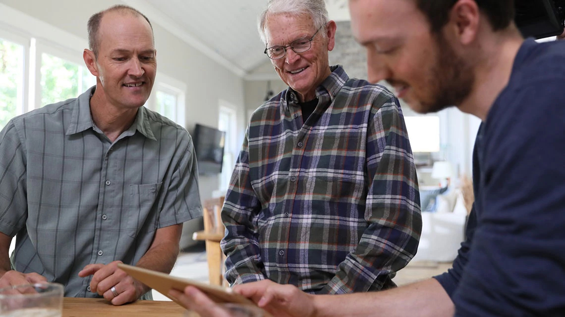 Three smiling men looking at tablet