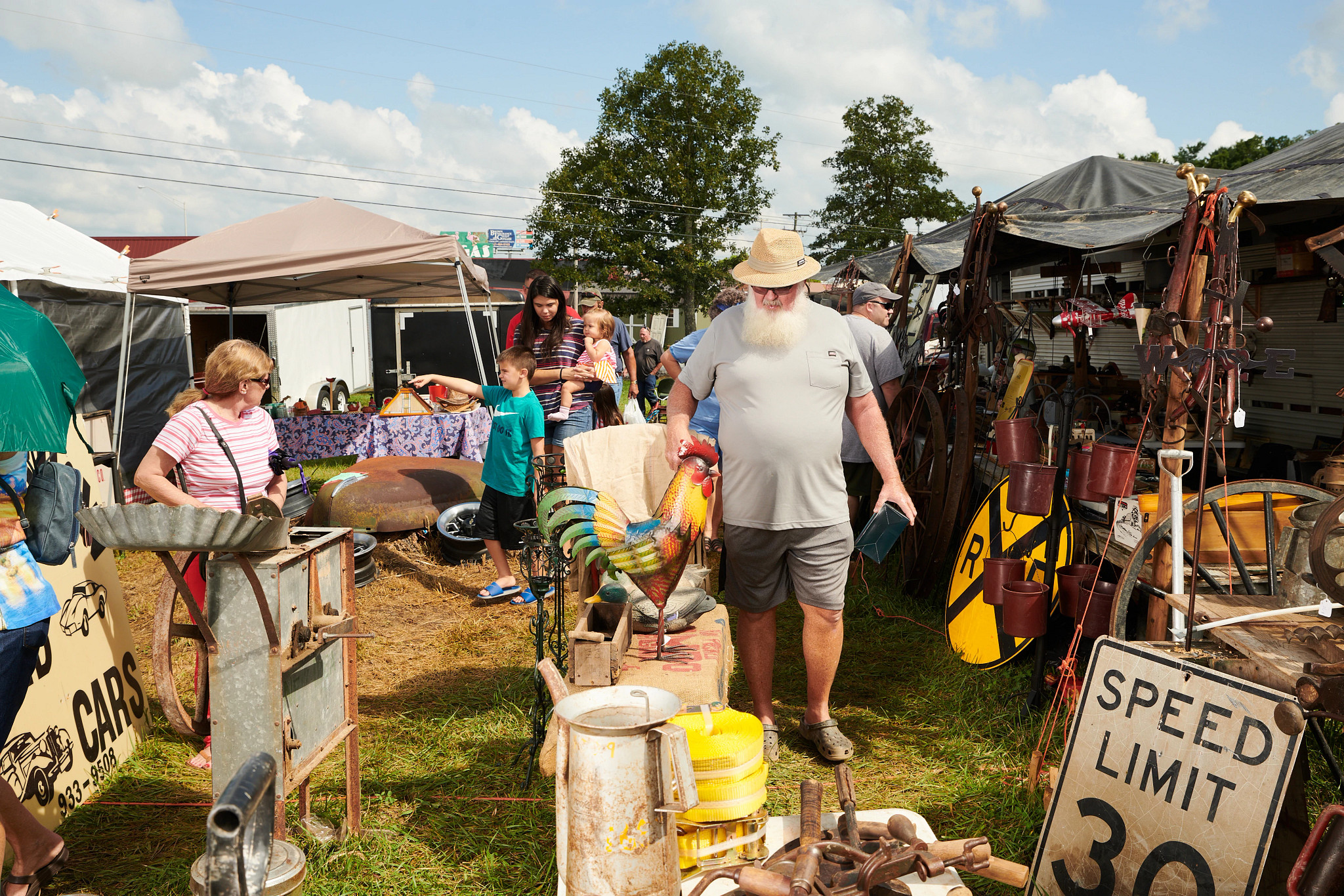 a man looking at a rooster figurine at a yard sale