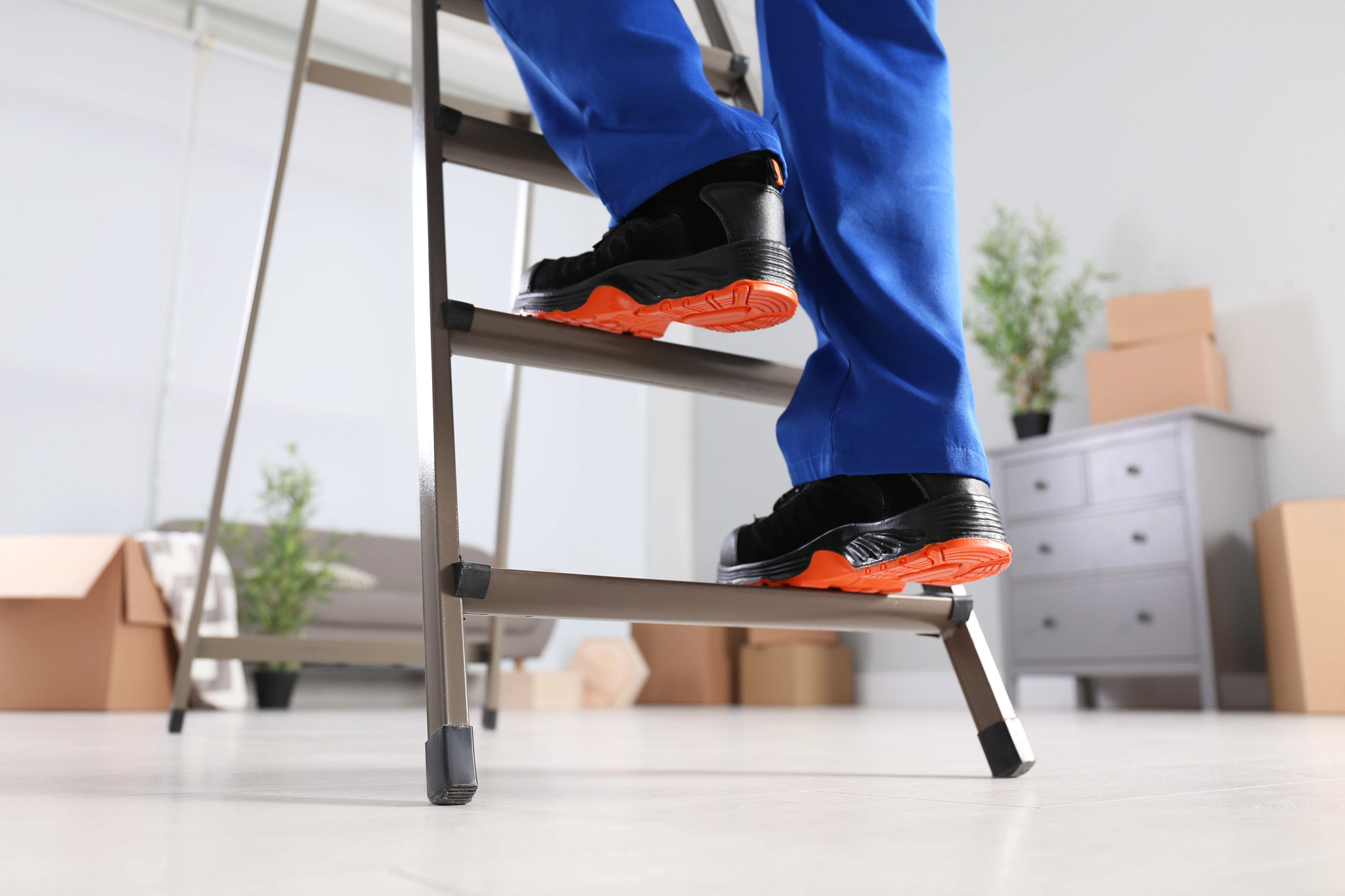 A man climbing up a ladder with orange-soles shoes