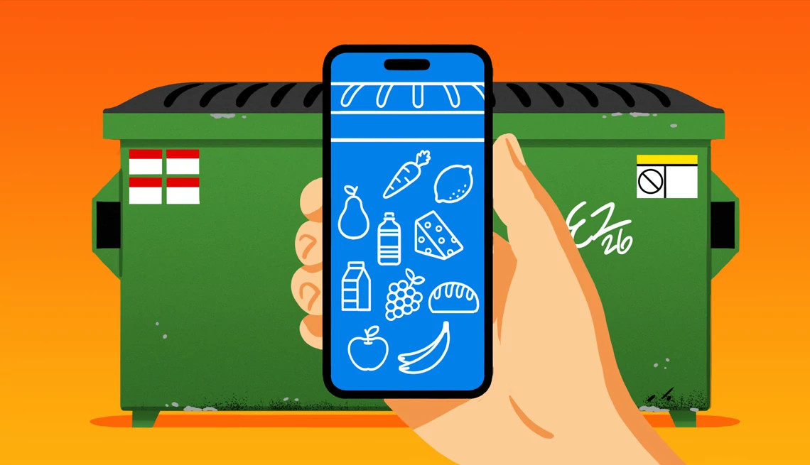 A hand holds a smartphone in front of a dumpster. Produce and other food staples are pictured on the phone screen.