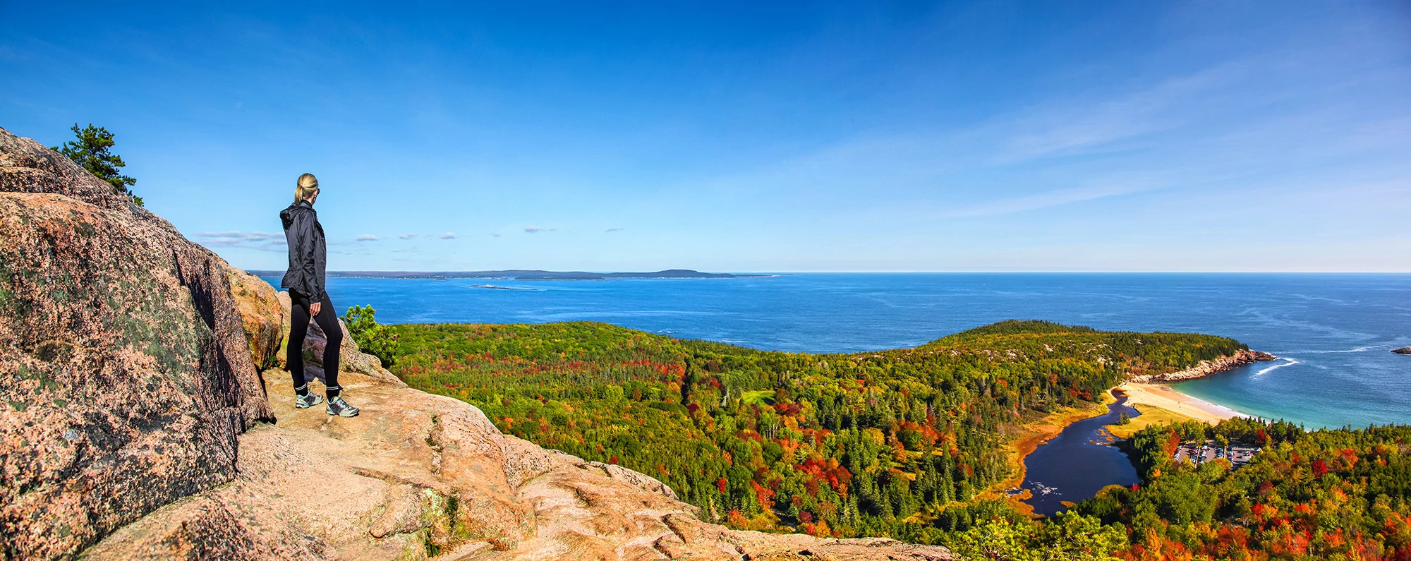 Hiker enjoying the panoramic view from the top of Beehive Trail in Acadia National Park