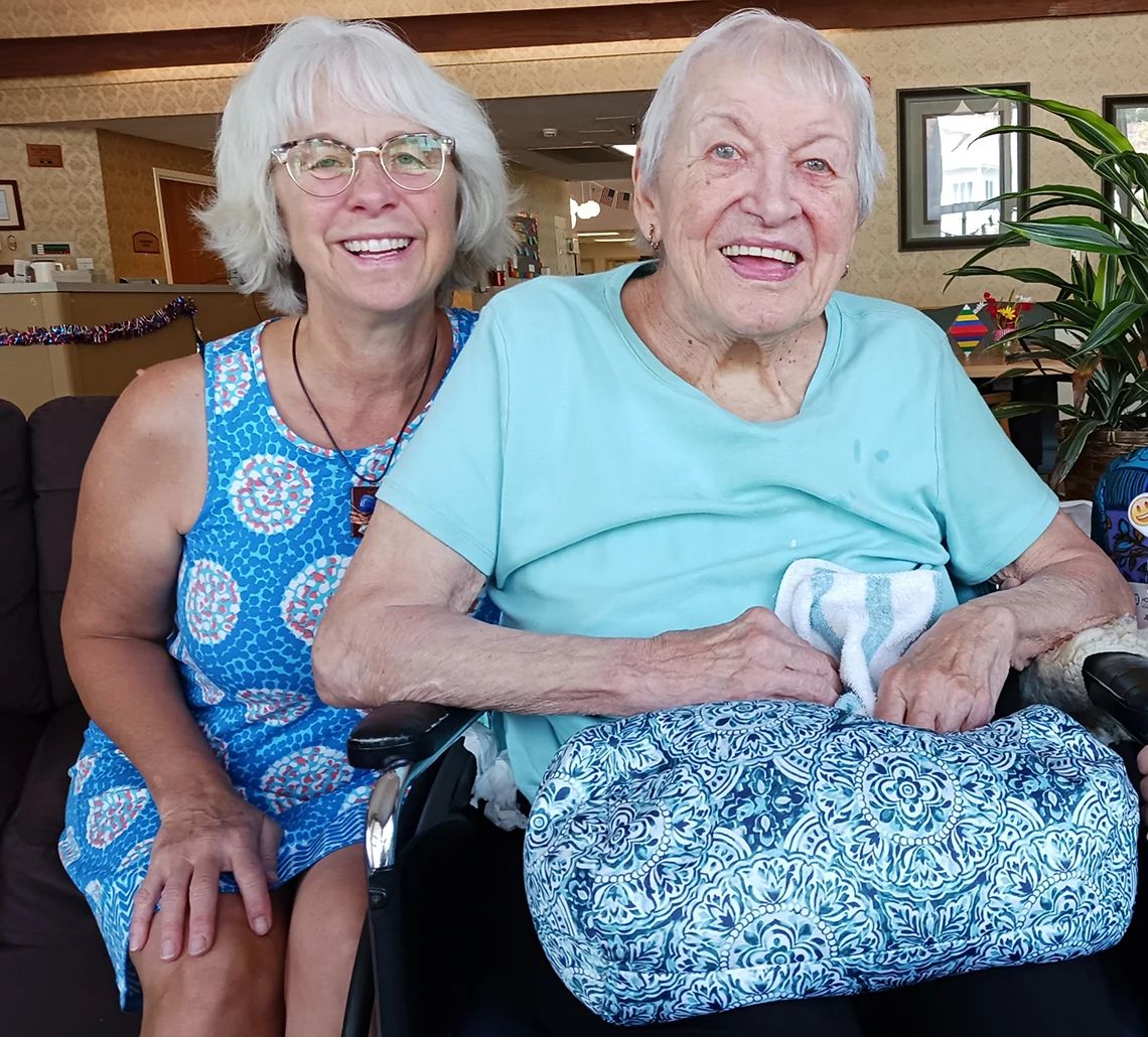 Sharon Wille Padnos, in a sleeveless blue dress, smiles next to her mother, Jean Wille.