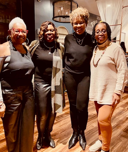 Four people smiling together at an Ethel essay celebration event in a restaurant