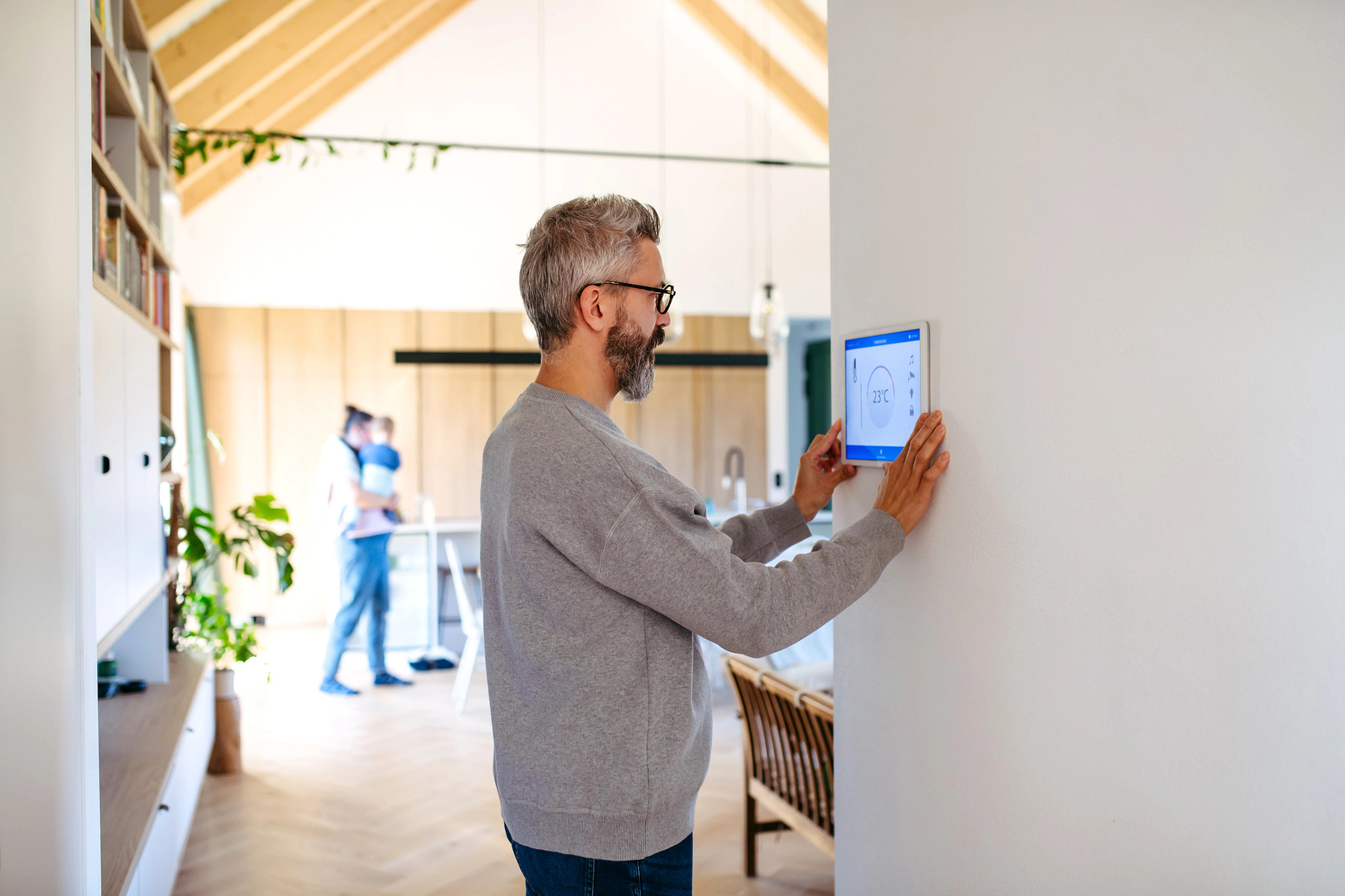 Man using smart home control panel, adjusting temperature.