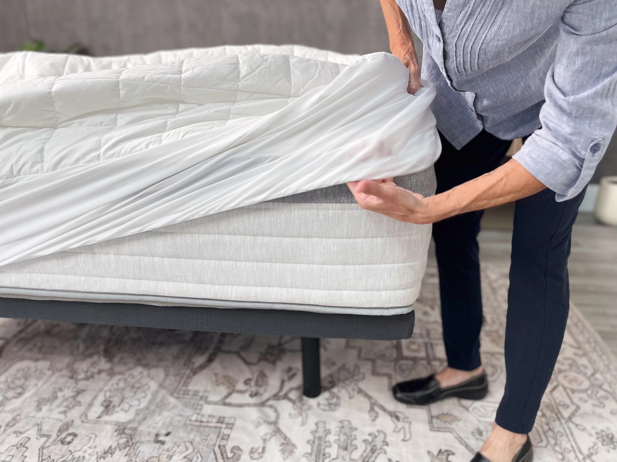 A woman pulling a mattress protector down on the corner of a mattress