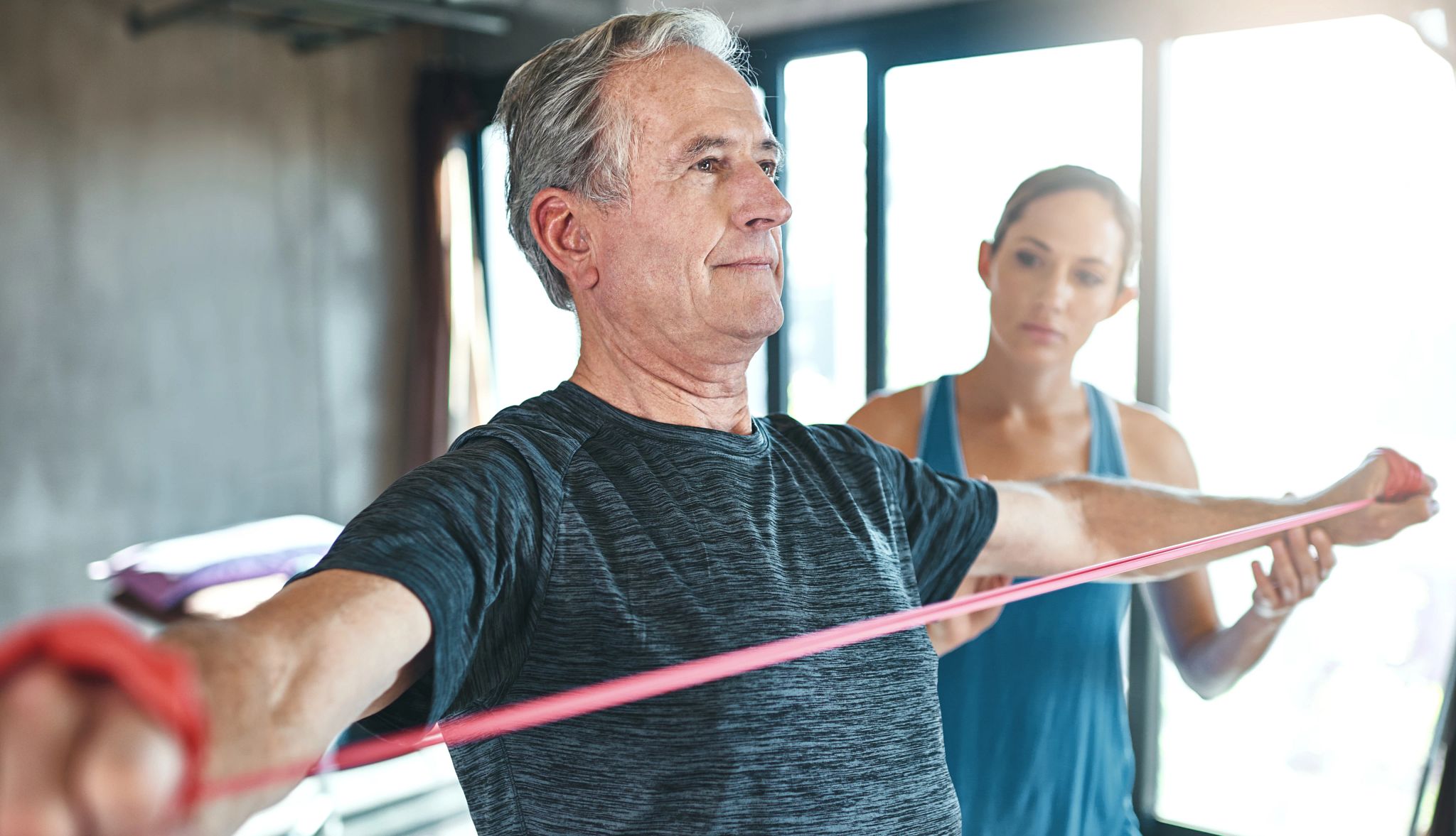 Older man and woman with strength training bands in the park Older man and woman with strength training bands in the park