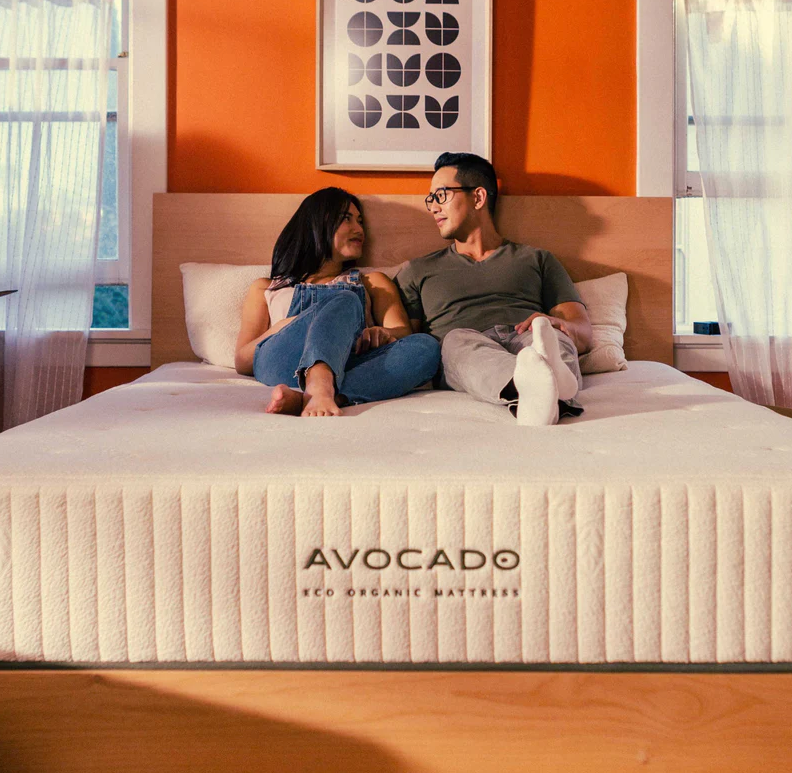 Two people sitting on the Avocado Eco Organic Mattress