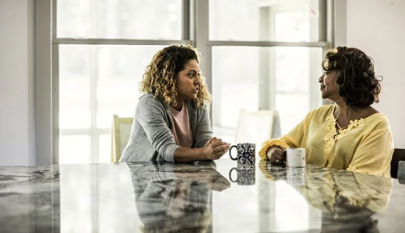A daughter and mother share a conversation over coffee.