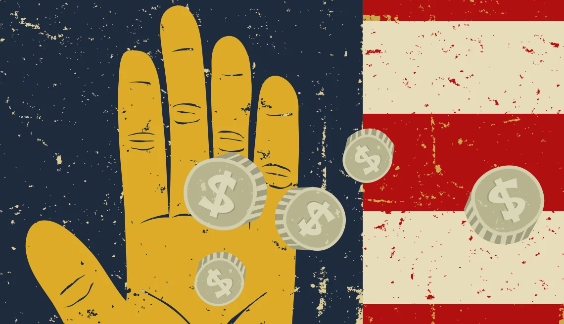 monedas caen en una mano, con la bandera estadounidense de fondo