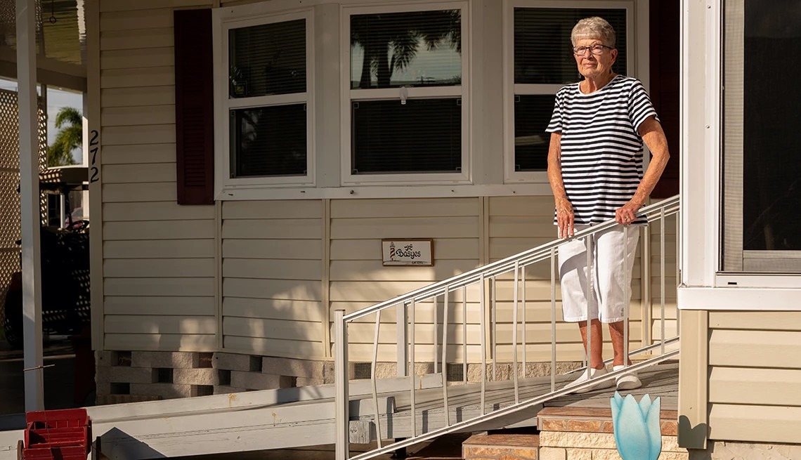 Senior Caucasian woman stands on a wheelchair ramp in front of her home