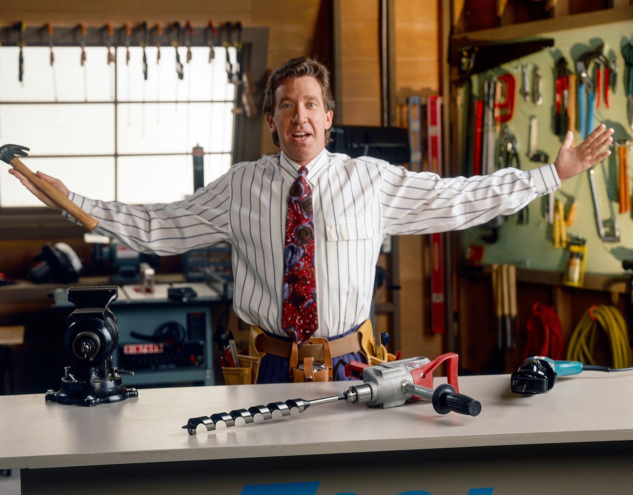 A confident Tim Allen, arms outstretched, showcasing tools in "Home Improvement.".
