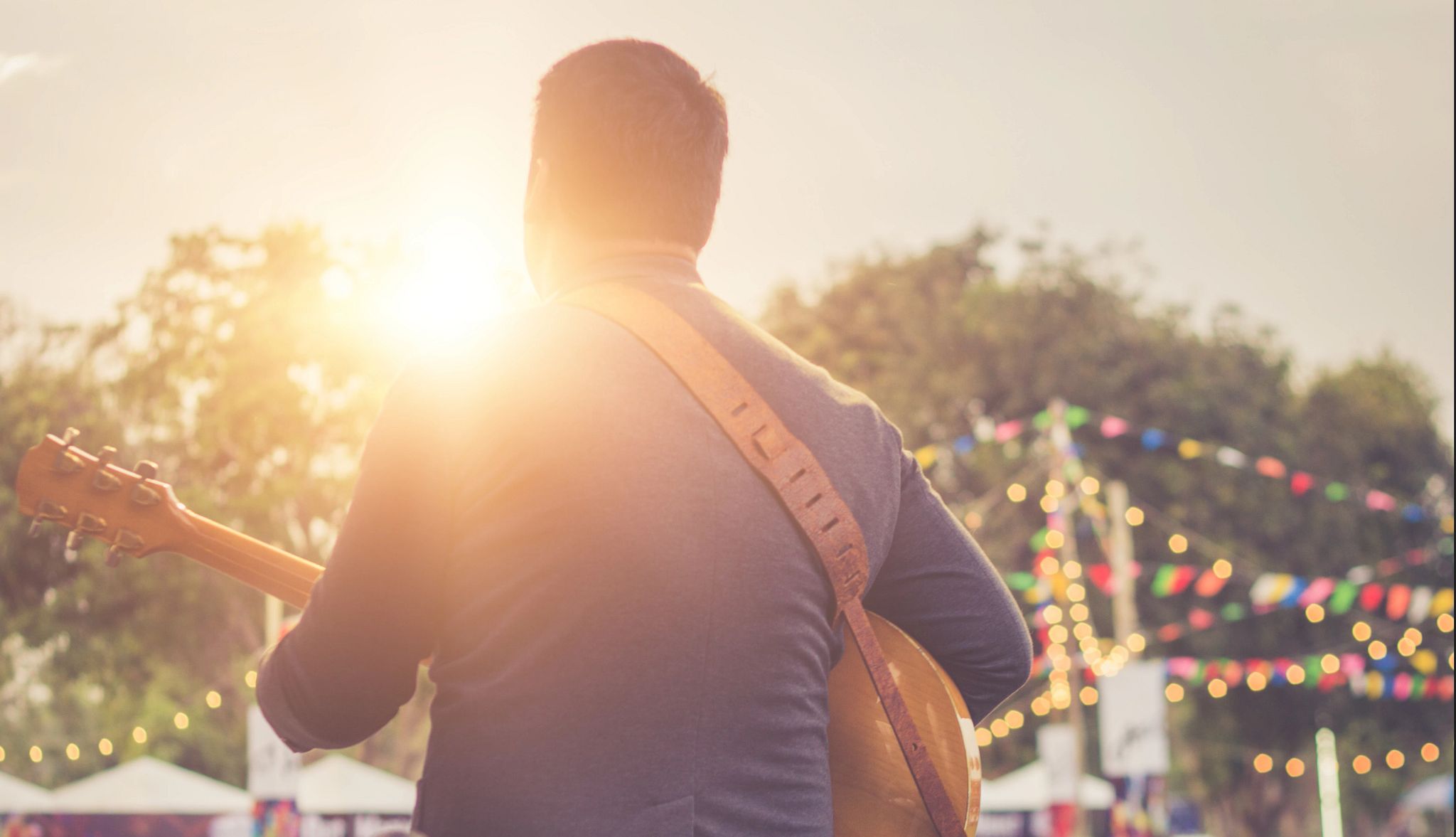 Musician playing guitar on outdoor stage. Musician playing guitar on outdoor stage.