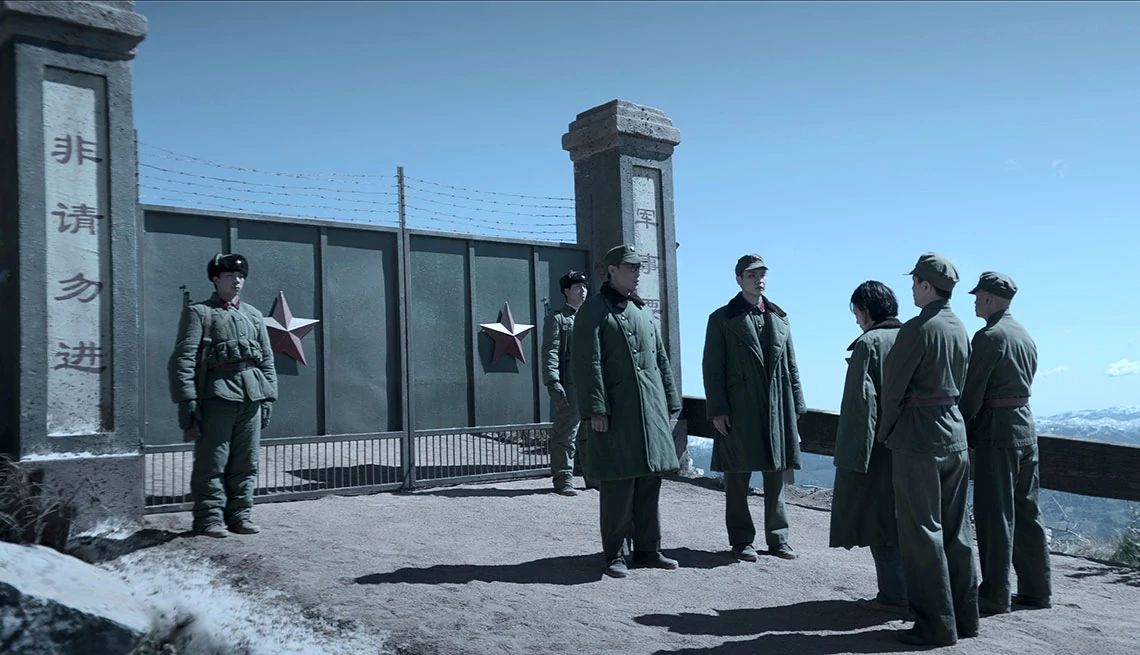 A scene from 3 Body Problem Yu Guming and Zine Tseng with a group of military personnel outside of a metal gate in the Netflix series 3 Body Problem
