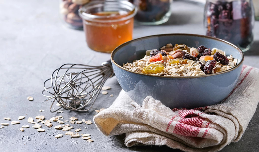A bowl of oatmeal with walnuts and other nuts in it on a gray blue table